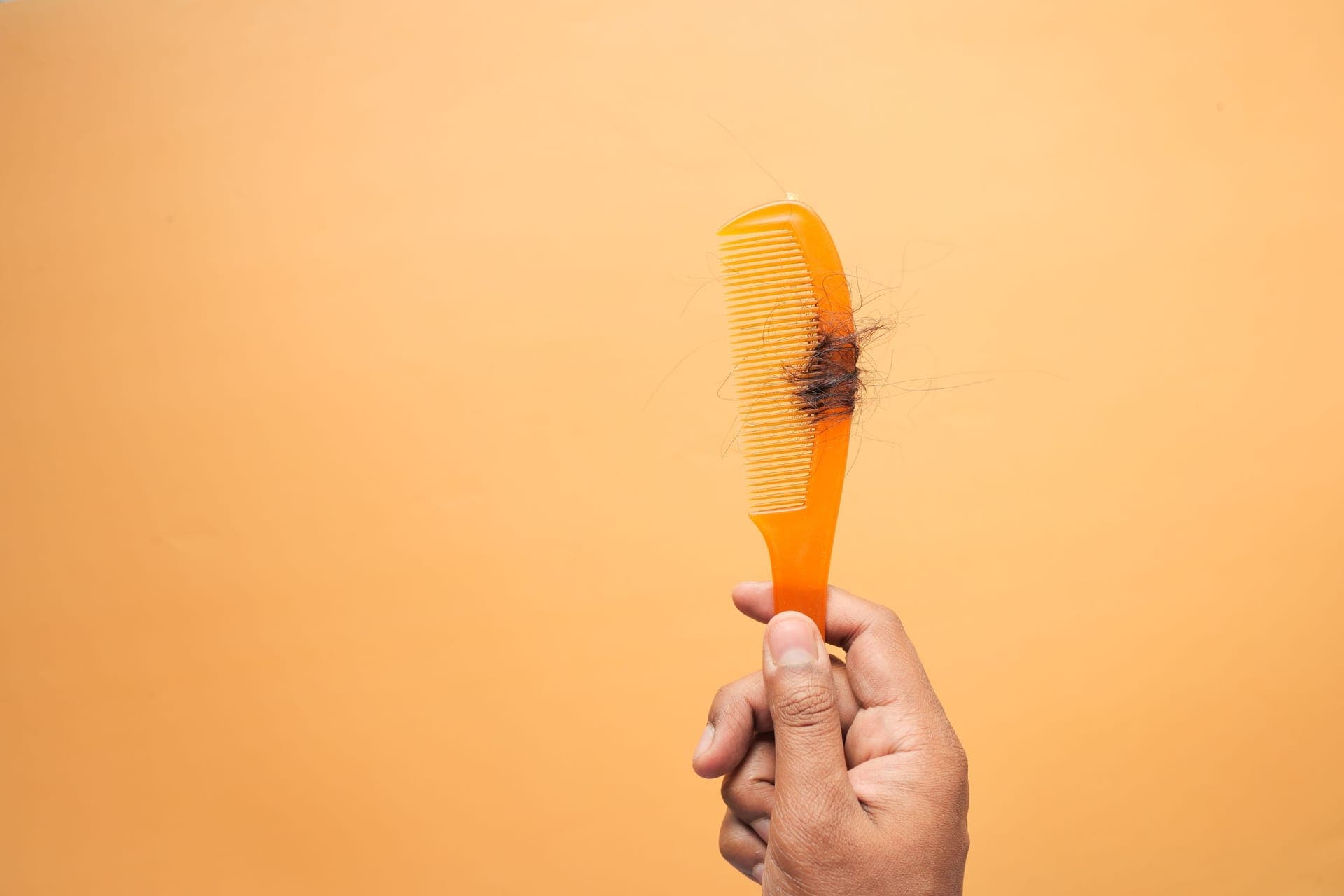 Close view of dry, split hair ends against a plain background